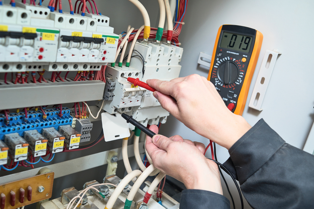 Joey Electric technician testing electrical panel with multimeter in Montreal
